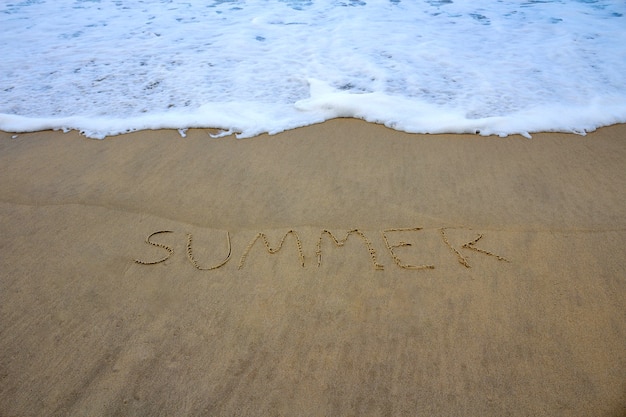 Mar con verano escrito en la arena de la playa