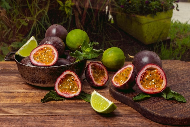 Maracujá inteiro e cortado ao meio ou gulupa ao lado de limões e hortelã sobre mesa de madeira envelhecida e fundo natural Passiflora edulis fo Edulis