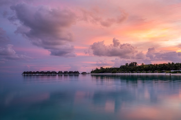 Maravilhosa paisagem panorâmica do pôr do sol Maldivas. Seascape de villas resort de luxo com reflexo do céu do mar