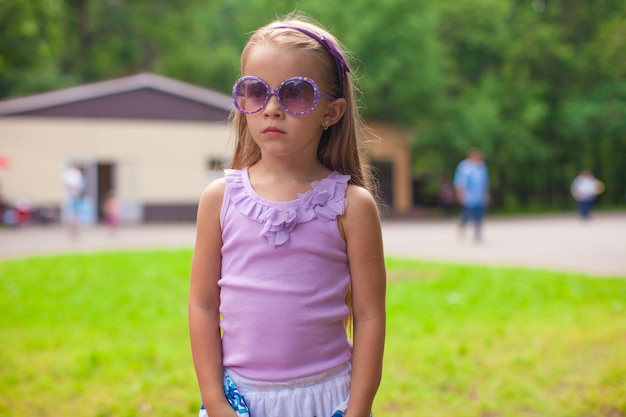 Maravillosa niña en gafas de sol caminando en el parque de verano