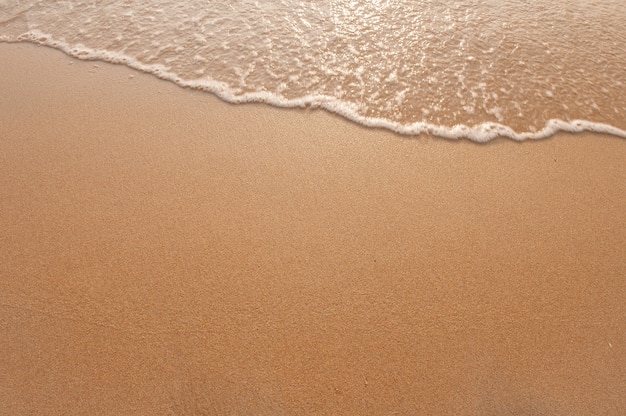 Maravillosa ola suave en la playa de arena con luz del sol en la mañana