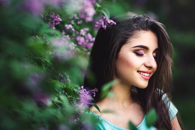 Maravillosa primavera. Linda chica joven disfruta de la naturaleza entre las lilas florecientes.