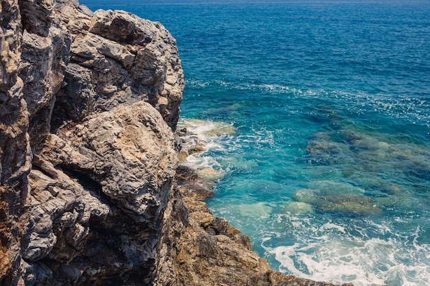 Maravillosas vistas del mar Mediterráneo azul Rocas soleadas olas con espuma y agua salpicada La ola choca contra las rocas en la orilla