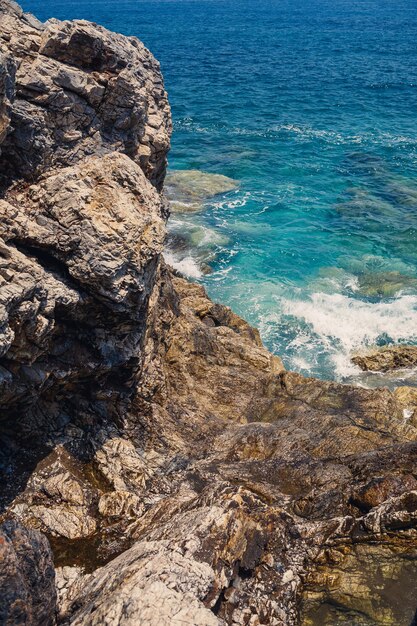 Maravillosas vistas del mar Mediterráneo azul Rocas soleadas olas con espuma y agua salpicada La ola choca contra las rocas en la orilla