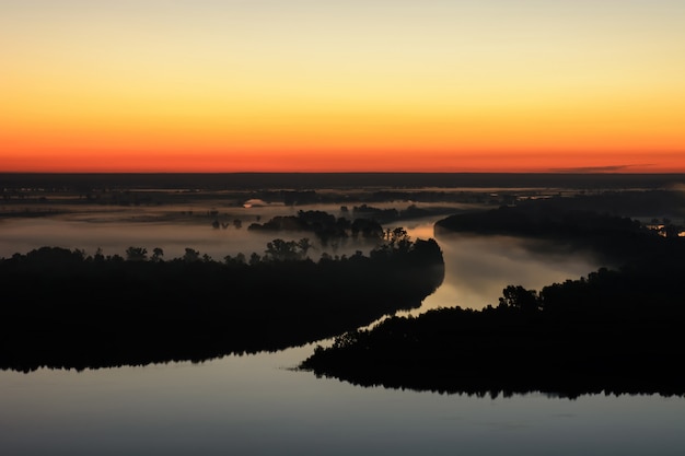 Maravilloso amanecer brumoso fantasmal sobre la silueta de la isla y el río brumoso.