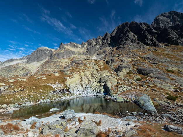 Foto maravilloso lago de montaña bajo un cielo azul increíble ricos colores amarillo rojo marrón de la roca de las montañas