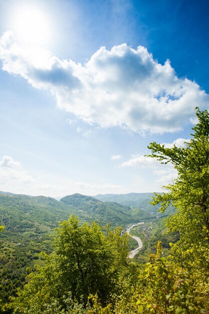 El maravilloso paisaje de la montaña verde está en el fondo del cielo azul nublado con un sol brillante.