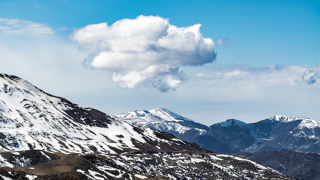 Maravilloso paisaje montañoso nevado con grandes rocas en densas nubes