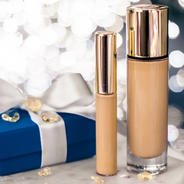 Marca cosmética brillo navideño y concepto de blog femenino maquillaje navideño base corrector base y caja de regalo azul cosméticos de lujo presente y productos de etiqueta en blanco para diseño de marca de belleza