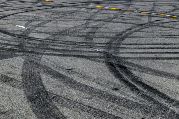 Marca de la pista del neumático en la textura y el fondo de la pista de carreras de la carretera de asfalto