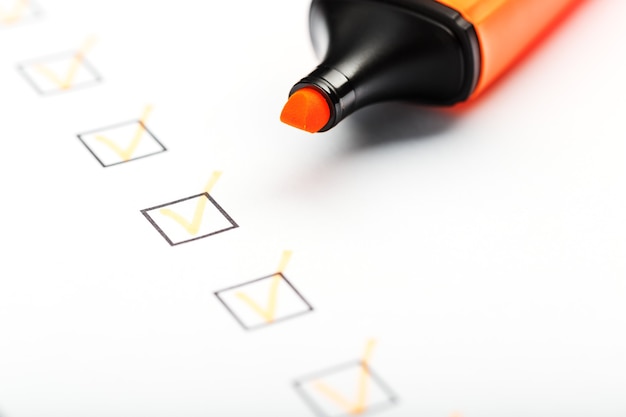Marcador laranja com marcadores na folha da lista de verificação. conceito de tarefa concluída da lista de verificação.