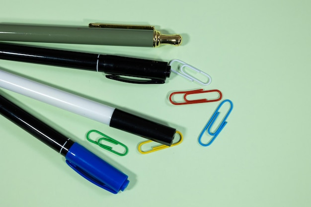 Marcadores, destacadores e clips de papel de várias cores espalhados sobre um fundo claro