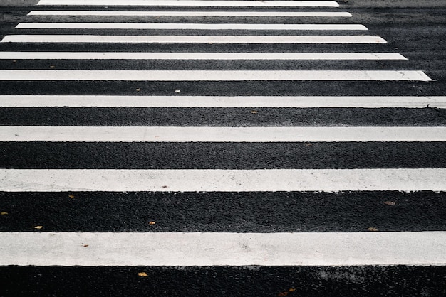 Marcas brancas listradas de uma travessia de pedestres no asfalto preto