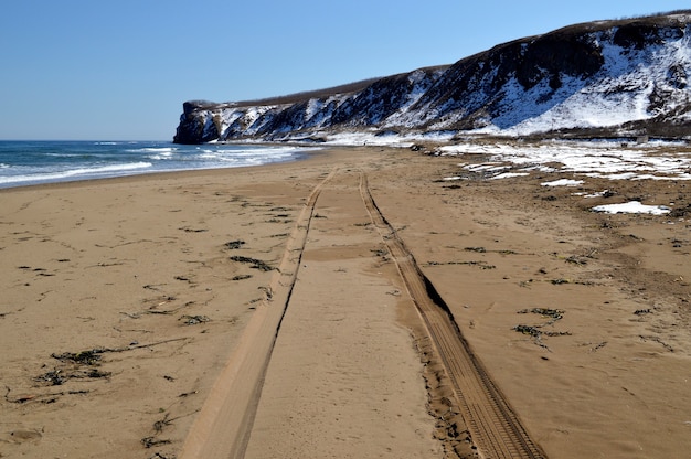 Marcas de neumáticos en la arena de una playa desierta del mar japonés