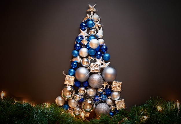 Un marco con un árbol de Navidad azul y plateado hecho con adornos, bolas y luces, póster