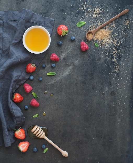 Marco de bayas con espacio de copia a la derecha Fresas frambuesas arándanos y hojas de menta fondo grunge oscuro