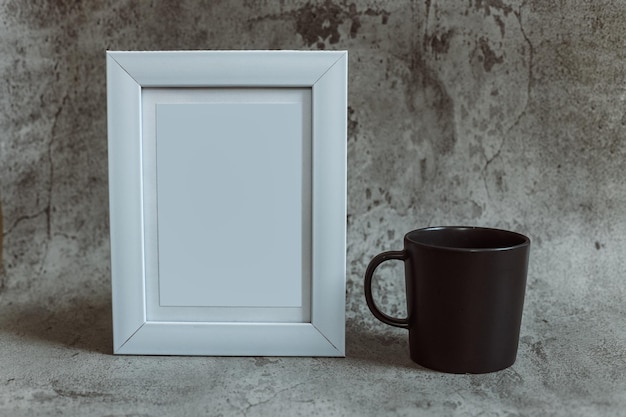 Marco blanco en blanco con una taza de café o té sobre un fondo gris