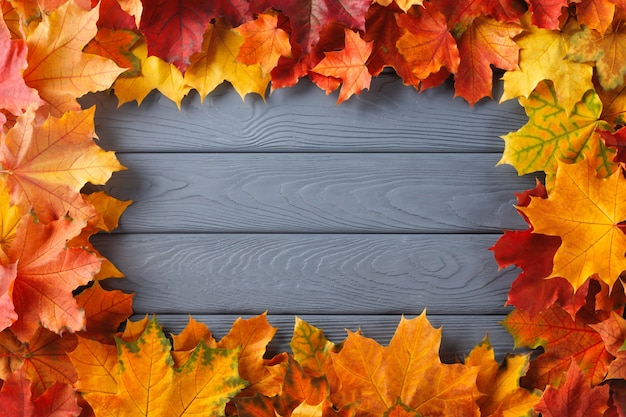 Foto marco de borde de coloridas hojas de otoño en madera con textura