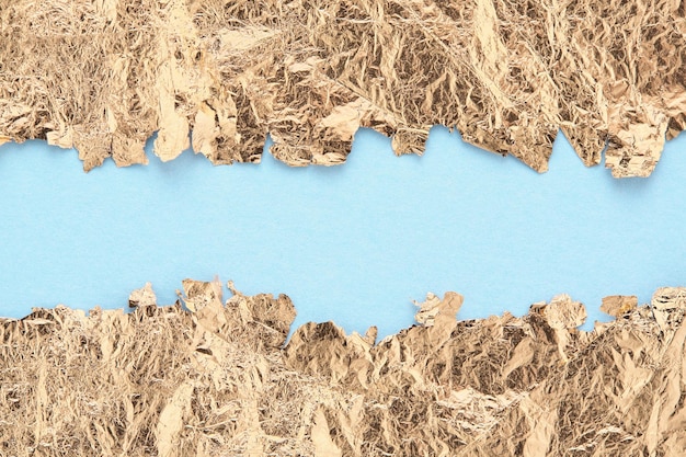 Marco de bordes rasgados de papel dorado, fondo abstracto azul, espacio de copia.
