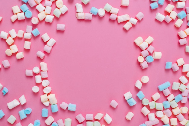 Marco de caramelos de malvavisco dulce blanco y rosa con espacio de copia sobre un fondo rosa.