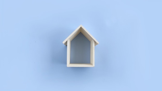 Marco de casa de madera sobre fondo azul Símbolo inmobiliario