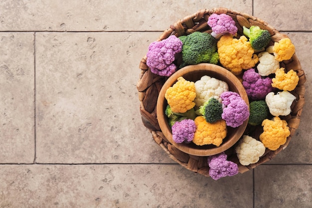 Marco de coliflor Colorfu Coliflor cortada en trozos pequeños en una caja o cesta sobre un fondo de baldosas de piedra gris antiguo Maqueta de marco Cocina de alimentos y concepto o fondo de cosecha agrícola