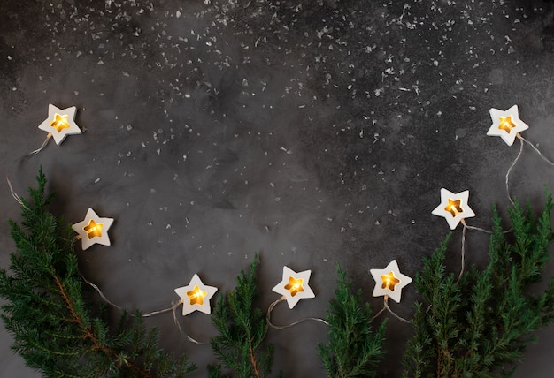 Marco de concepto de Navidad o año nuevo con decoraciones de vacaciones de invierno. Fondo oscuro con una guirnalda ardiente. copia espacio