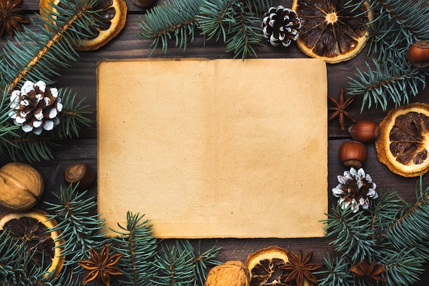 Marco de conos de árbol de Navidad naranjas nueces sobre fondo de madera oscura. Copia espacio Endecha plana. Papel viejo para texto.