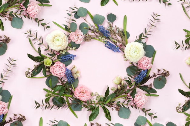 Foto marco de corona de flores con ramas frescas de rosas en forma de pión y hojas de eucalipto aisladas sobre fondo blanco, plano y vista superior