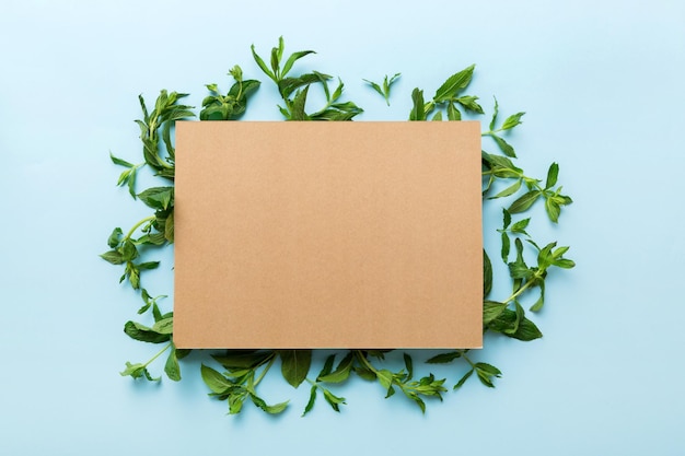 Marco de corona hecho de papel vacío en blanco con espacio para texto y hojas de menta sobre fondo de color Patrón de menta Endecha plana Vista superior