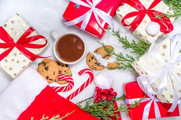 Marco de diseño creativo con muchas cajas de regalo, ramas de árboles de Navidad, piñas, taza de chocolate caliente, dulce de Navidad, tablet pc sobre fondo blanco de piel esponjosa. Fondo de preparación de Navidad y año nuevo