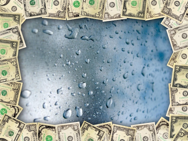 Foto marco de los dólares en la superficie con gotas de agua.