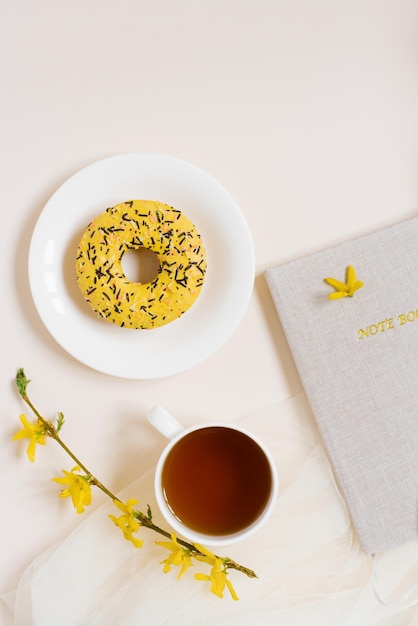 Marco de espacio de trabajo de oficina en casa con bloc de notas taza de té donut pluma Vista superior de posición plana Espacio de copia