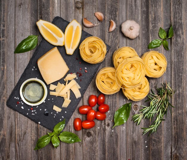 Marco de fondo de fettuccine con ingredientes para cocinar pasta en la vista superior de madera envejecida