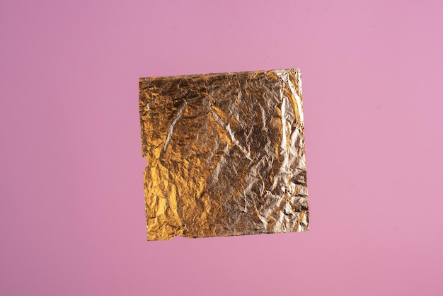 Foto marco de fondo de un trozo de hoja de oro sobre papel rosa