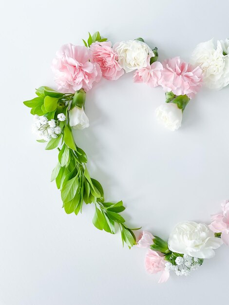 Foto marco en forma de corazón de claveles blancos rosados