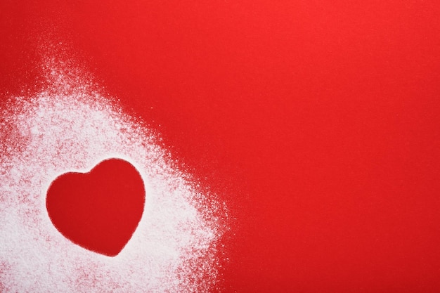 Marco en forma de corazón hecho de harina sobre fondo rojo. Feliz día de San Valentín, día de la madre. Concepto de panadería de regalo de San Valentín para tarjeta o diseño creativo. Vista superior.