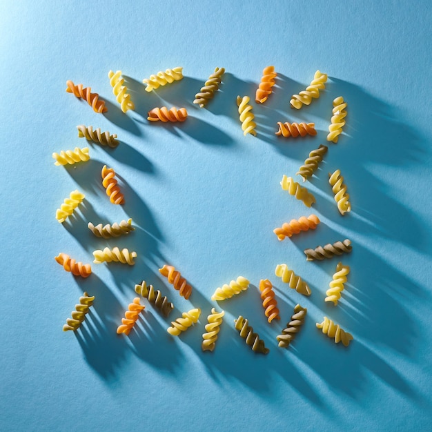 Foto marco en forma de cuadrado de pasta multicolor sobre un fondo azul plano laical