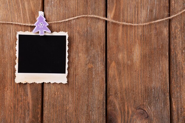 Foto marco de fotos en blanco y decoración navideña en cuerda sobre fondo de madera