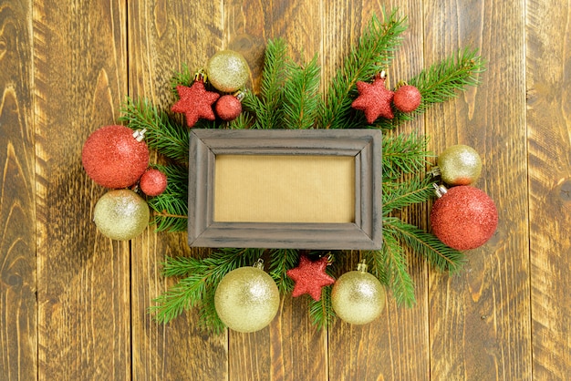 Marco de fotos entre la decoración de Navidad, con bolas de color dorado y estrellas sobre una mesa de madera marrón. Vista superior, marco para copiar espacio.