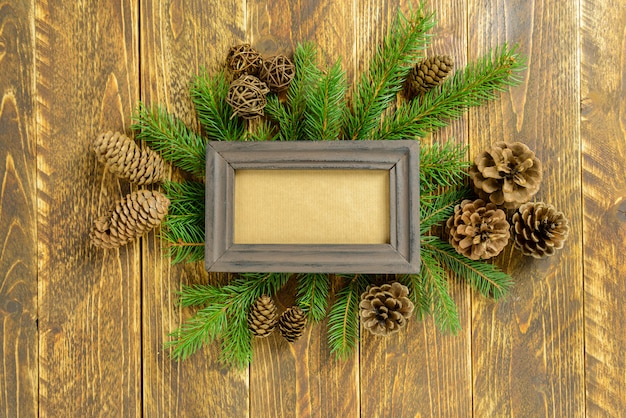 Marco de fotos entre la decoración de Navidad, con piñas en una mesa de madera marrón. Vista superior, marco para copiar espacio.