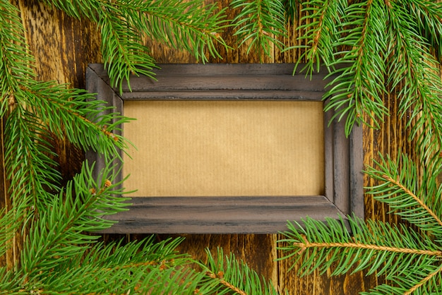 Foto marco de fotos entre la decoración de navidad, rama de pino verde sobre una mesa de madera marrón. vista superior, marco para copiar espacio.