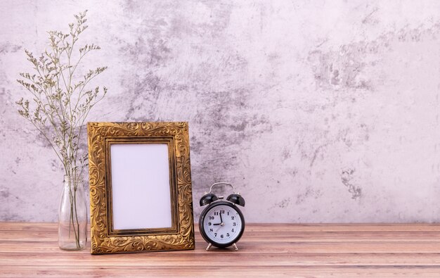 Marco de fotos y flores y reloj en mesa de madera