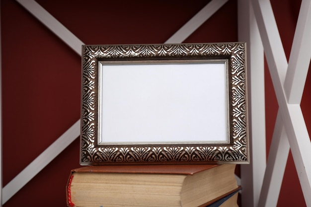 Marco de fotos con libros en el estante sobre fondo de pared de color