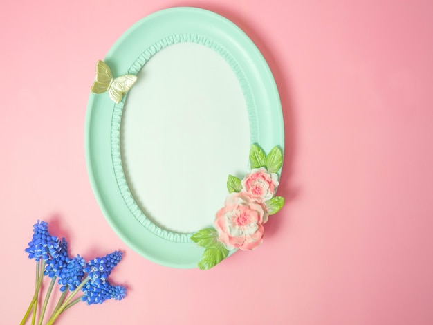 Marco de fotos turquesa vacío sobre un fondo rosa con flores de color púrpura estilo vintageEspacio de copia de marco de fotos ovalado