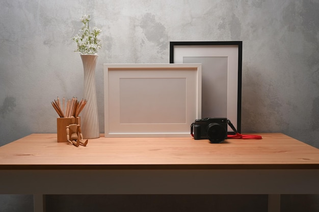 Marco de fotos vacío portalápices y cámara en escritorio de madera