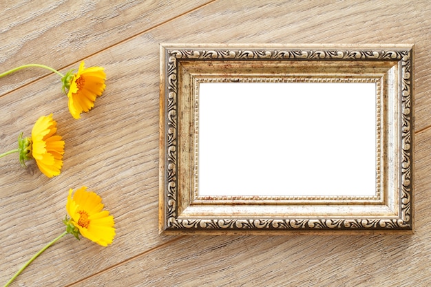 Marco de fotos vintage con espacio de copia y flores amarillas sobre tablas de madera antiguas.