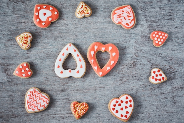 Marco con glaseado y decoración de galletas en forma de corazón sobre fondo gris. Concepto de comida del día de San Valentín