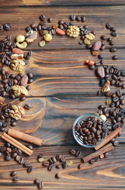 Marco de granos de café, pasas, nueces y canela sobre fondo de madera natural con espacio de copia para su texto