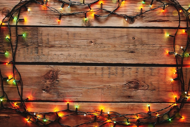 Marco de guirnalda de Navidad sobre fondo de madera.